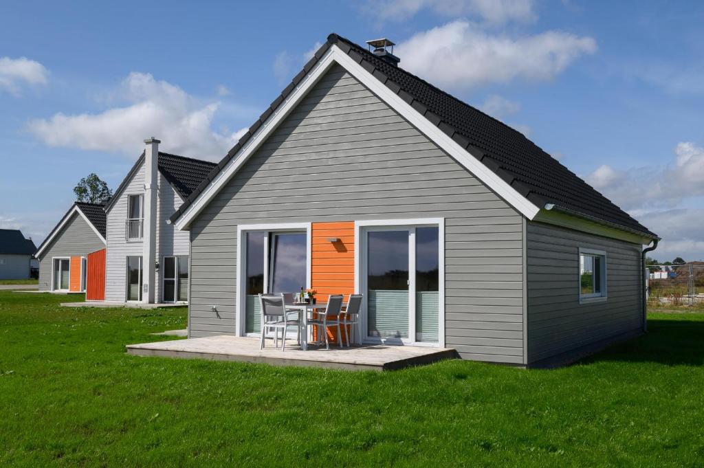 una casa gris con una mesa y sillas en un porche en Strandhaus 37, en Olpenitz