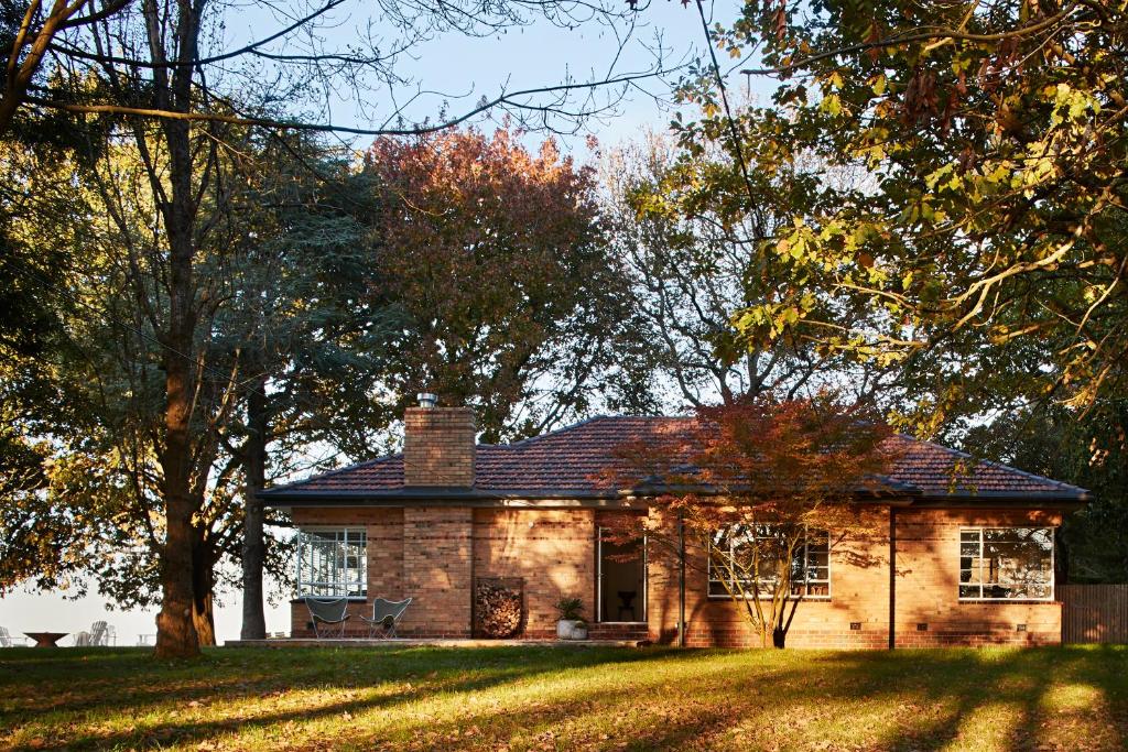 a brick house on a grassy yard with trees at Polperro Farmhouse in Red Hill