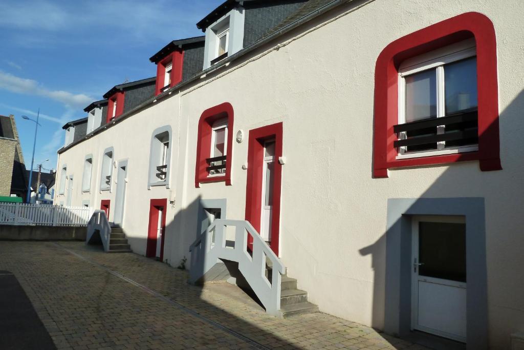 un bâtiment blanc avec des fenêtres rouges et un escalier dans l'établissement Appartement Fontaine Morgat, à Crozon