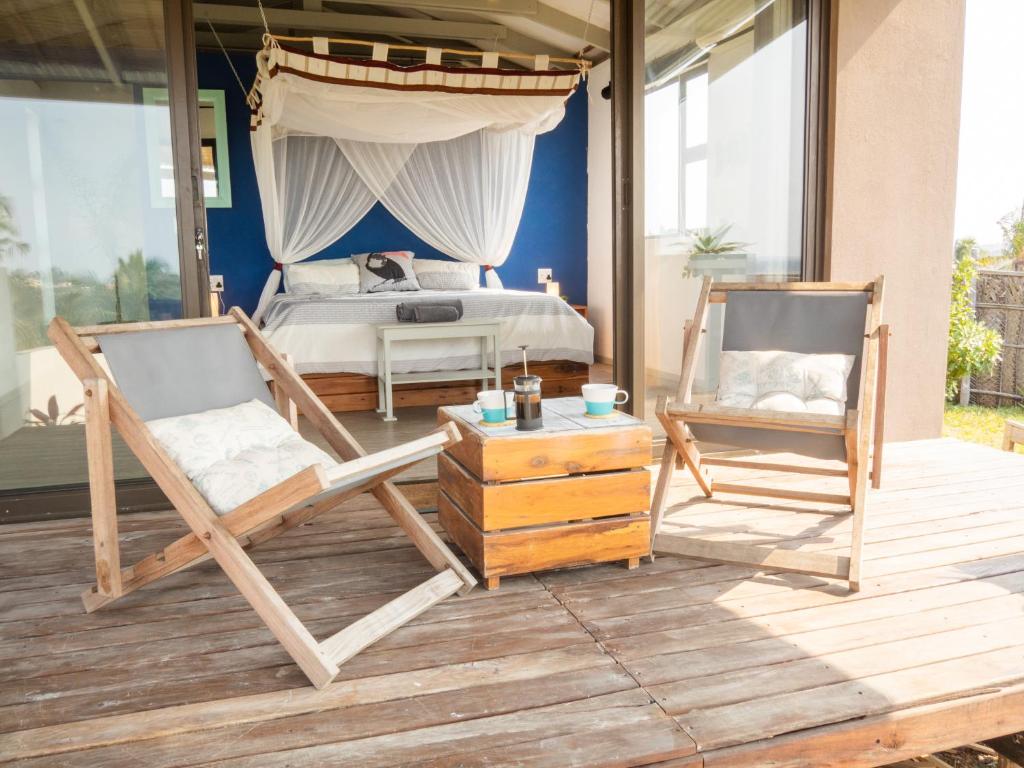 um quarto com uma cama e 2 cadeiras num deque em Casa Narinho em Praia do Tofo