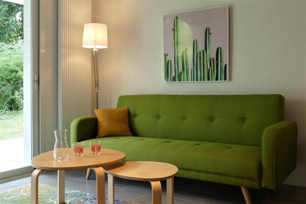 sala de estar con sofá verde y 2 mesas en BaskoParadis I Apt I Central I Calme I Lumineux I Lit 160 I Terrasse I Jardin, en Cambo-les-Bains