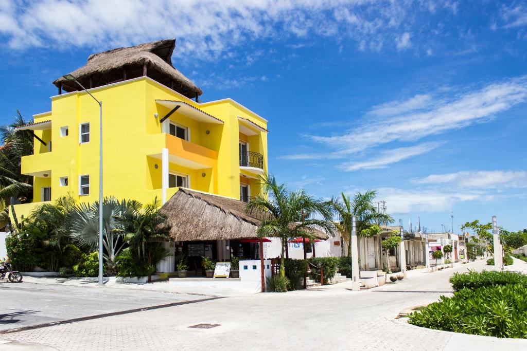 a yellow building with a thatched roof on a street at Hotel Sol Playa in Playa del Carmen