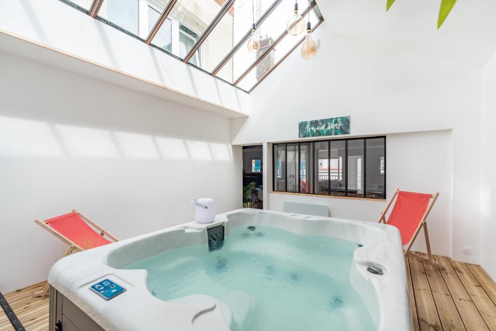 a hot tub in a room with two chairs at L'appart in Le Touquet-Paris-Plage