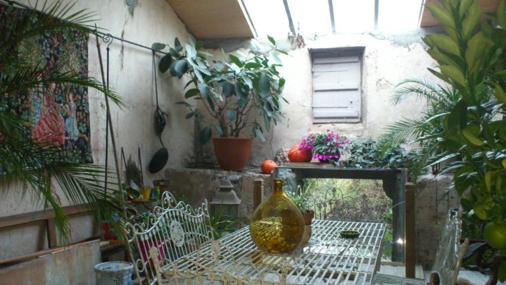 a patio with a table with a vase and plants at Chambre d&#39;hôtes Le Moulin de Moulis in Moulis-en-Médoc