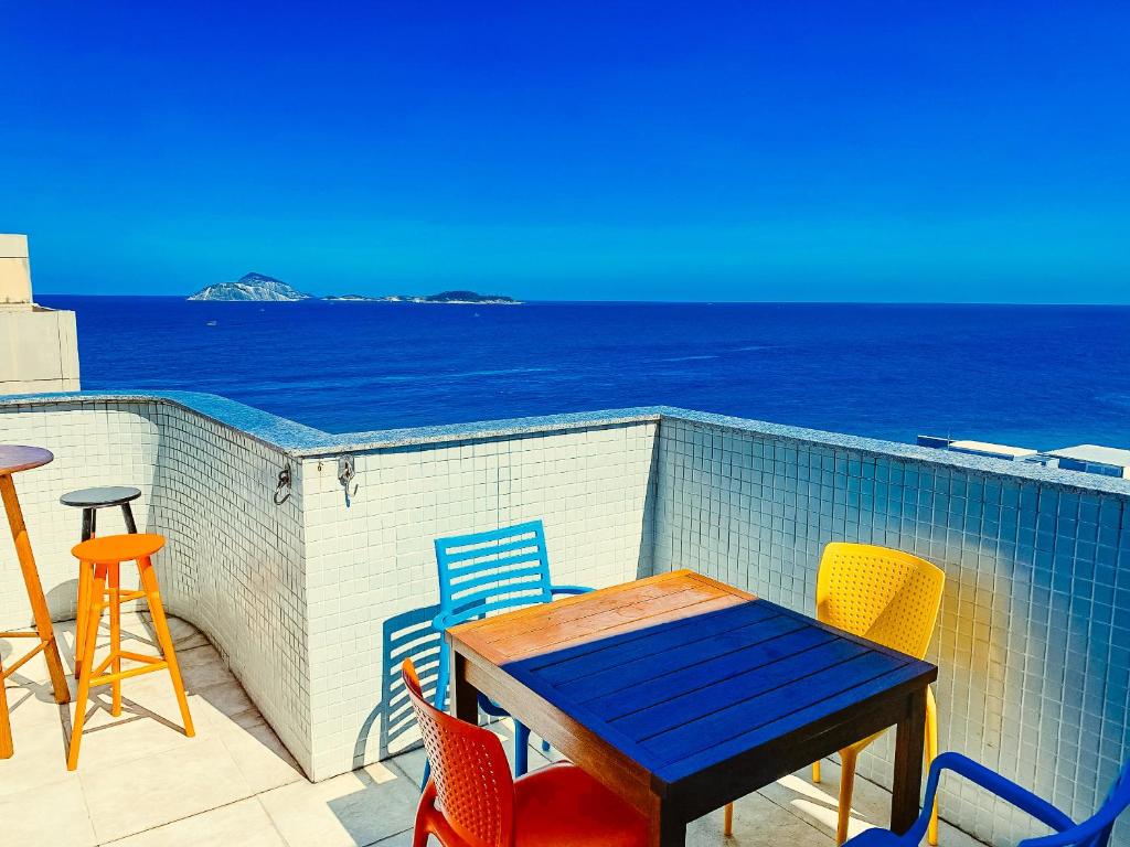 uma mesa e cadeiras numa varanda com vista para o oceano em Seaview Penthouse Arpoador no Rio de Janeiro