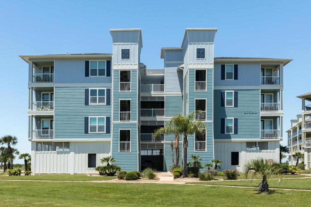 a blue apartment building with palm trees in front of it at Beach Retreat in Galveston