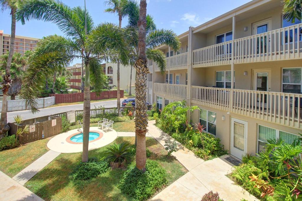 an apartment building with palm trees and a courtyard at Surfside Condos in South Padre Island