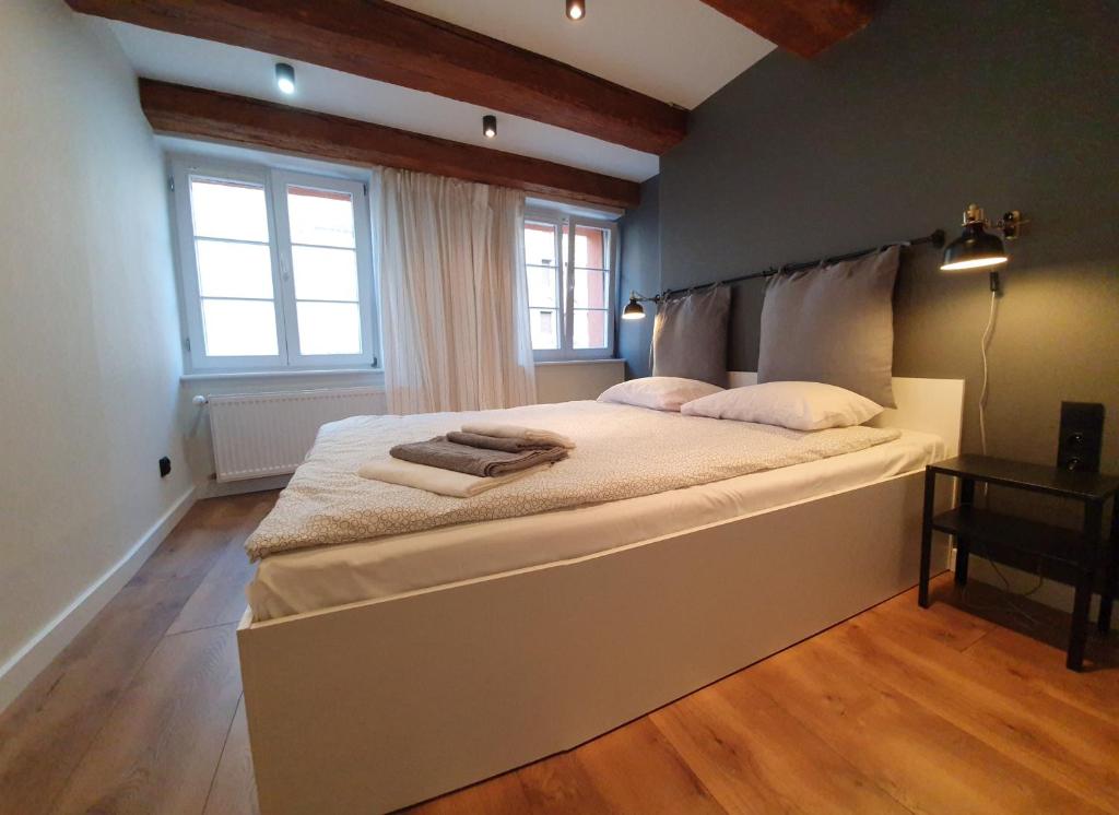 duże łóżko w pokoju z 2 oknami w obiekcie Apartament na starówce Toruń w Toruniu