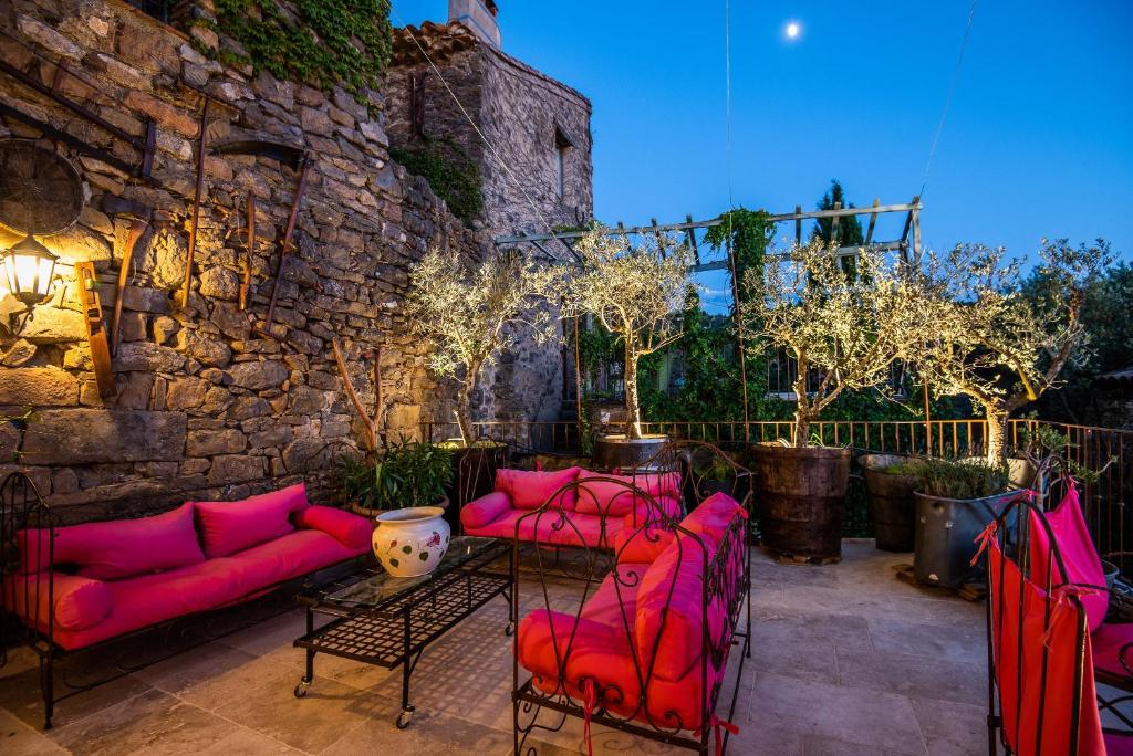 a patio with pink furniture and a stone wall at Chambre et Gite Le Roc sur l&#39;Orbieu in Carcassone