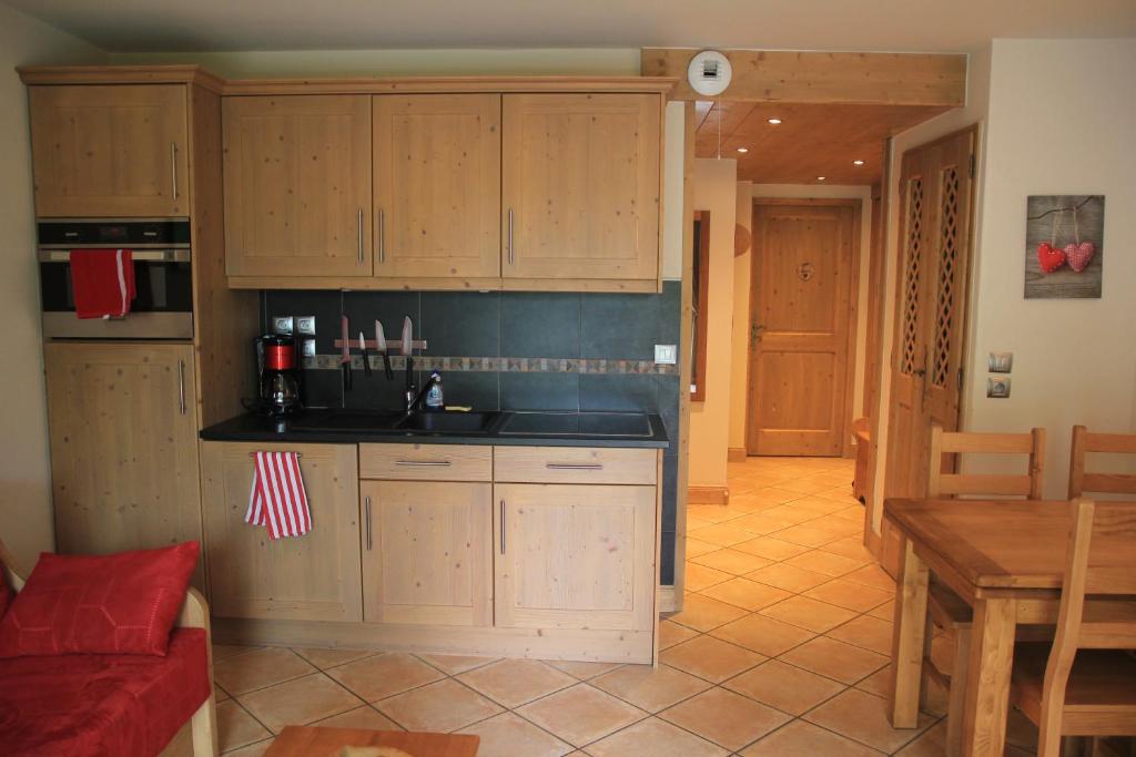 uma cozinha com armários de madeira, um sofá vermelho e uma mesa em At Home em Les Carroz d'Arâches