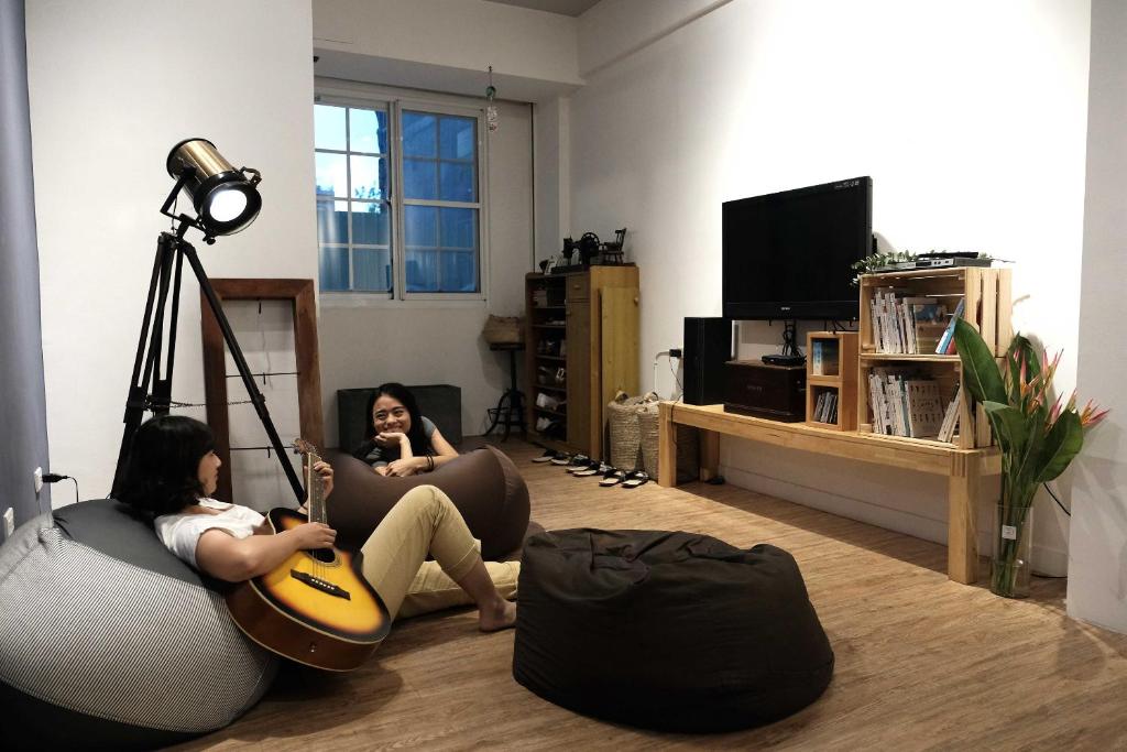 two women sitting on bean bags in a living room with a guitar at Backpacker 41 Hostel - Kaohsiung in Kaohsiung