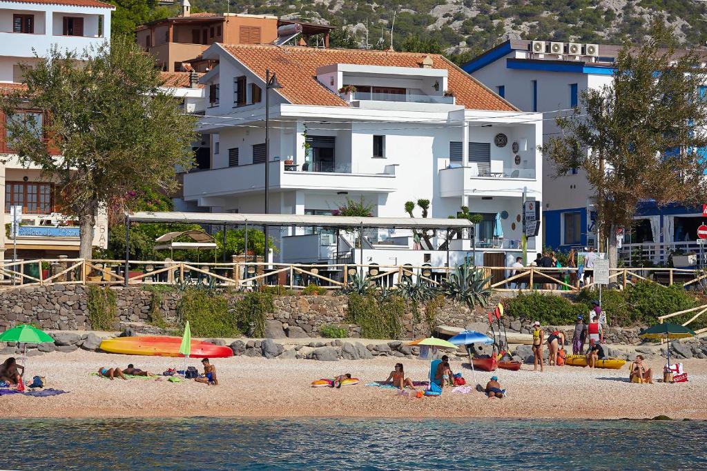 un grupo de personas en una playa cerca del agua en Appartamenti Jlune en Cala Gonone