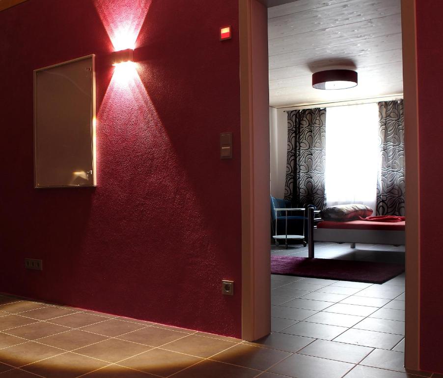 a hallway with a red wall with a mirror at Stundenhotel Lustra in Landshut