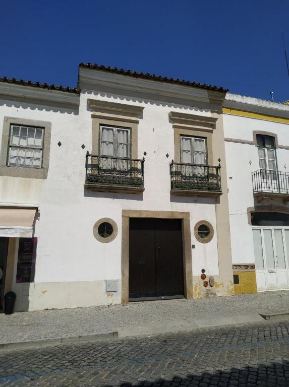 a white building with two balconies on a street at Casa da Lagoa Guest House in Évora