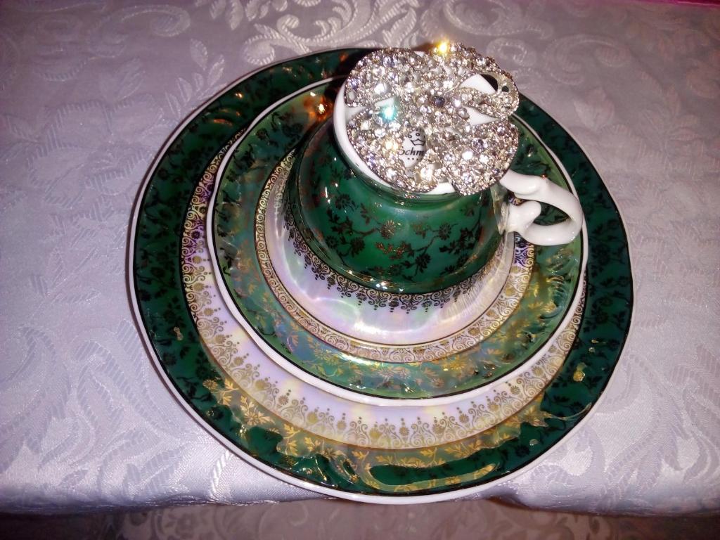 a green and gold plate with a coffee cup on it at La Petite France in Nova Petrópolis