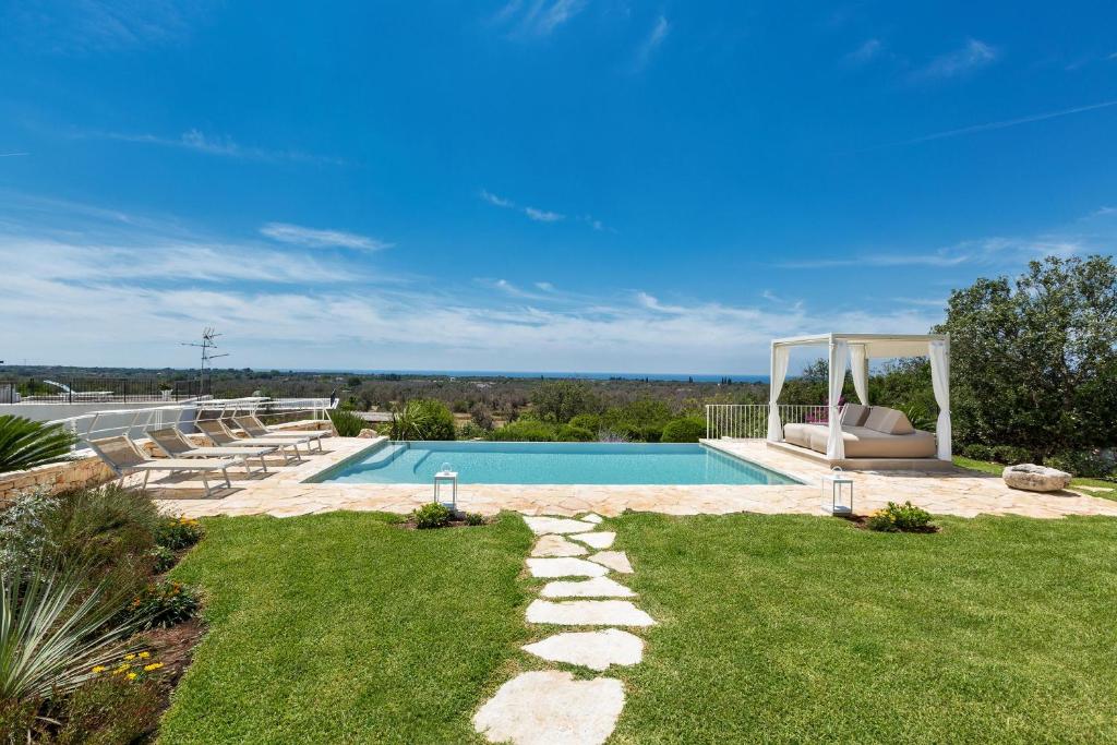 um quintal com uma piscina com um sofá e relva em Villa Elaion by BarbarHouse em Marina di Pescoluse