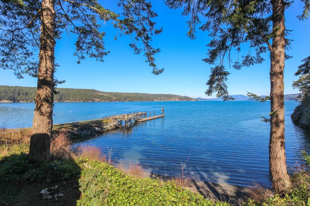 a dock on a lake with trees at Lopez Island Hunter Bay Waterfront Home in Lopez