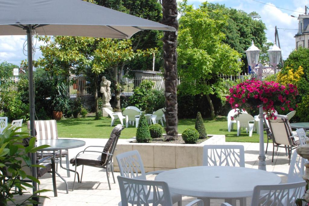 un patio avec des tables et des chaises et une fontaine dans l'établissement Hôtel Ariane & SPA, à Pontorson