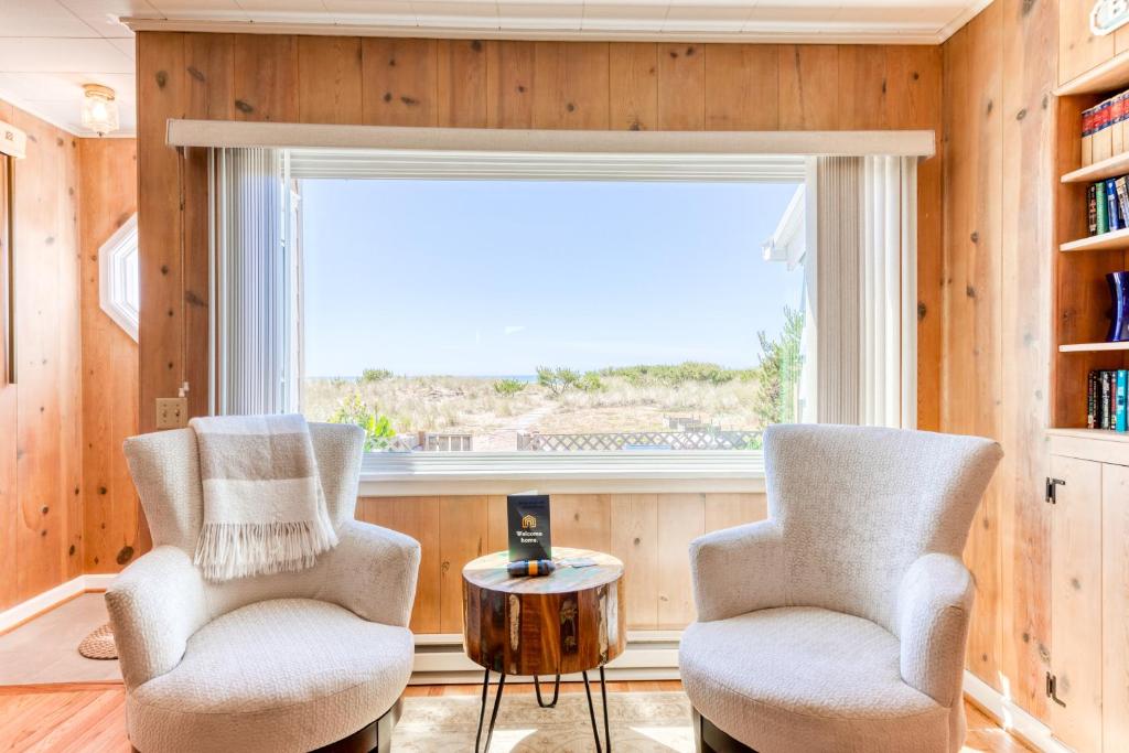two chairs and a table in a room with a window at Cheri's Oceanfront Getaway in Rockaway Beach