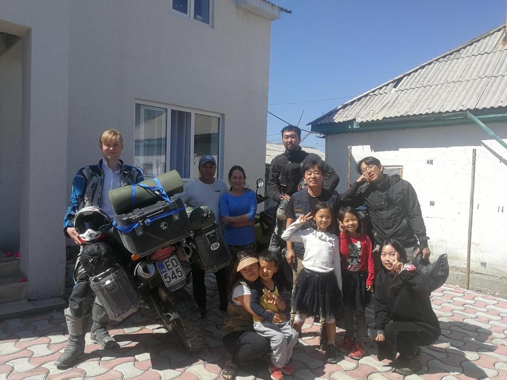 a group of people posing for a picture next to a motorcycle at Snow Leopard Hostel in Karakol