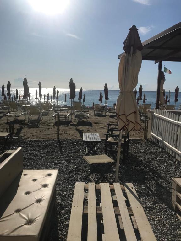 a beach with a bunch of chairs and an umbrella at Casa del sasso in Bergeggi