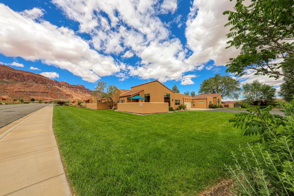 una casa en un césped verde con una carretera en Rim Village T2, en Moab