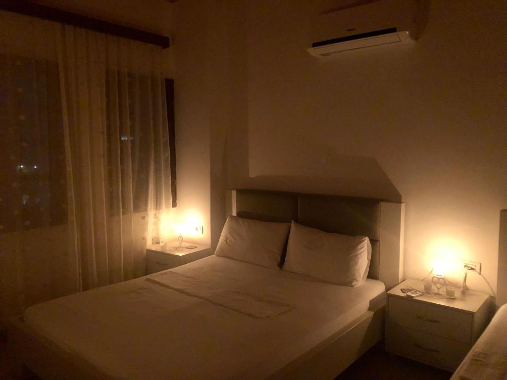 a bedroom with a white bed with two lights on it at Dhimitri's guest house in Berat