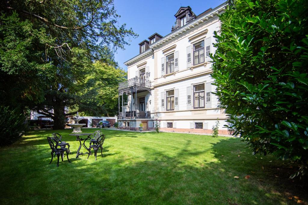 un groupe de chaises assises devant un bâtiment dans l'établissement Villa Luttwitz, à Baden-Baden