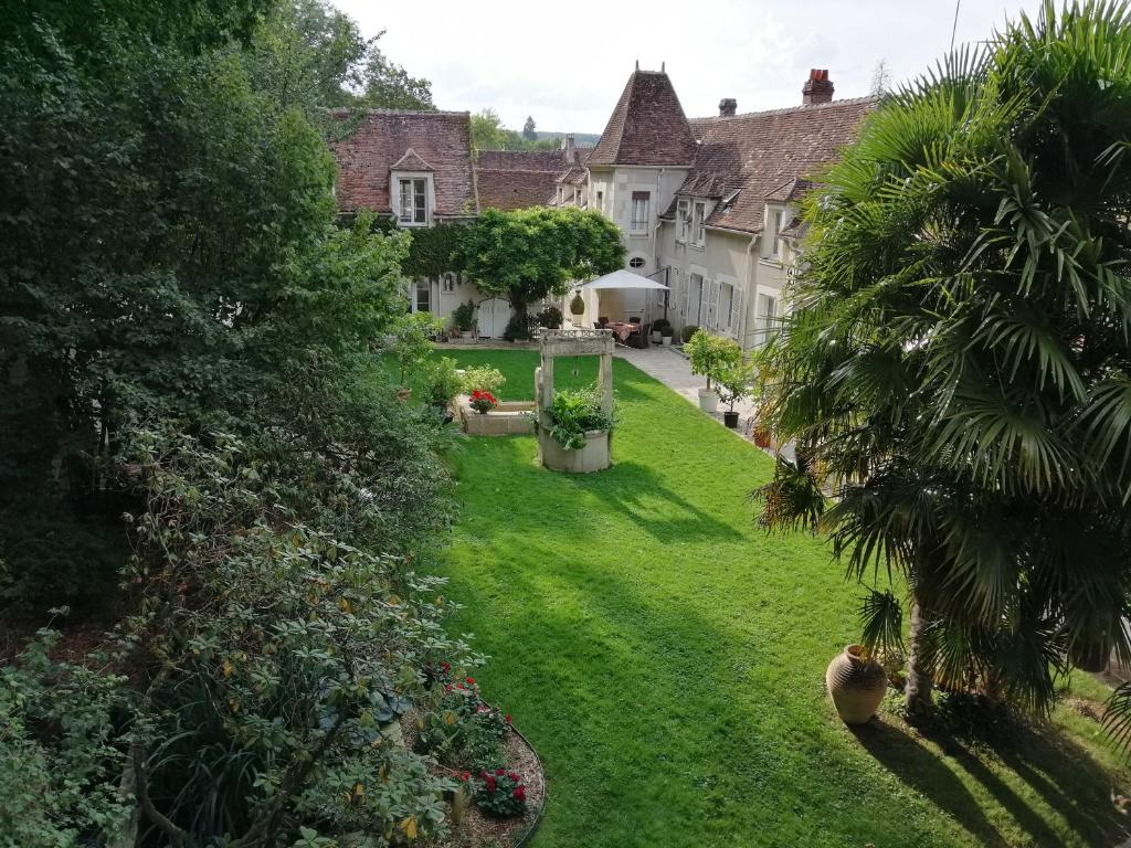 une maison dotée d'une cour avec de l'herbe verte et des arbres dans l'établissement Chambres et Tables d'hôtes du Puits d'Athie, à Appoigny