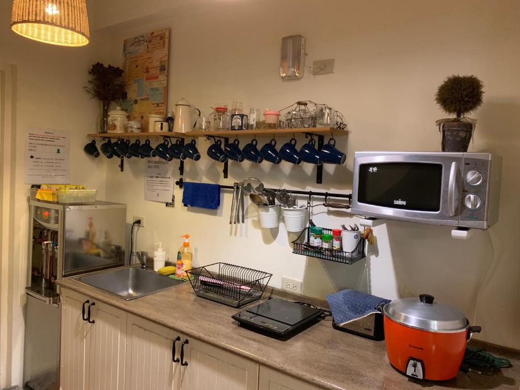 a kitchen counter with a sink and a microwave at Backpacker 41 Hostel - Kaohsiung in Kaohsiung