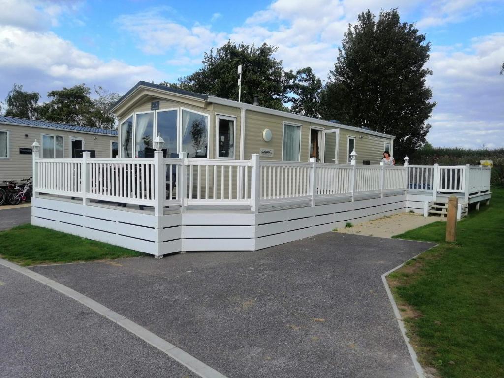 a house with a white fence and a porch at Caravan for rent at Tattershall Holiday Park in Tattershall