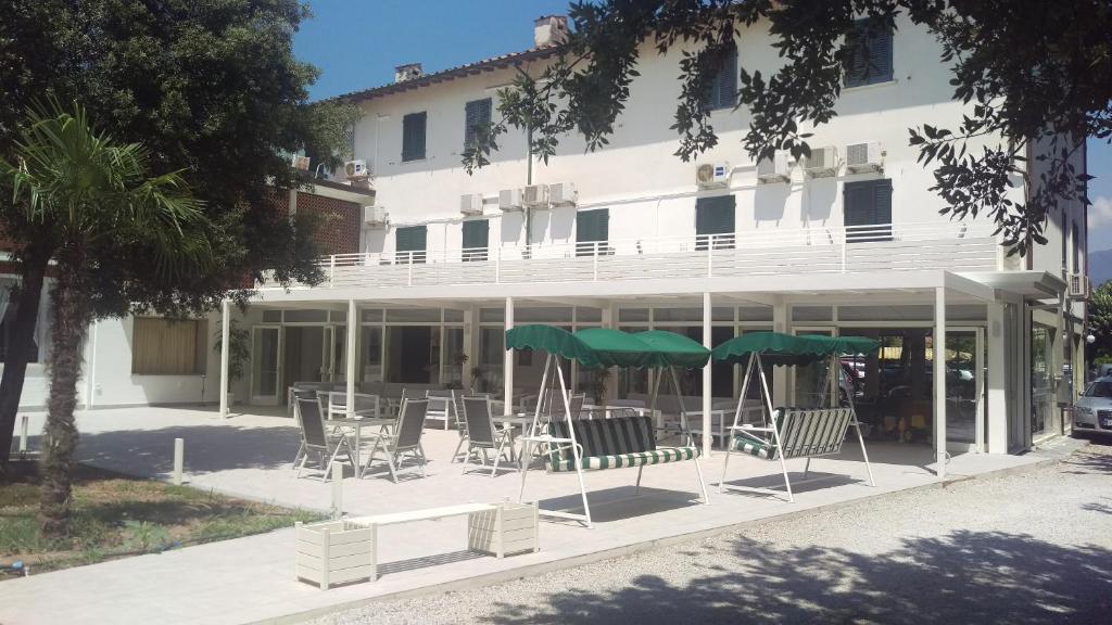 a patio with chairs and umbrellas in front of a building at Hotel Raffaelli Villa Angela in Forte dei Marmi