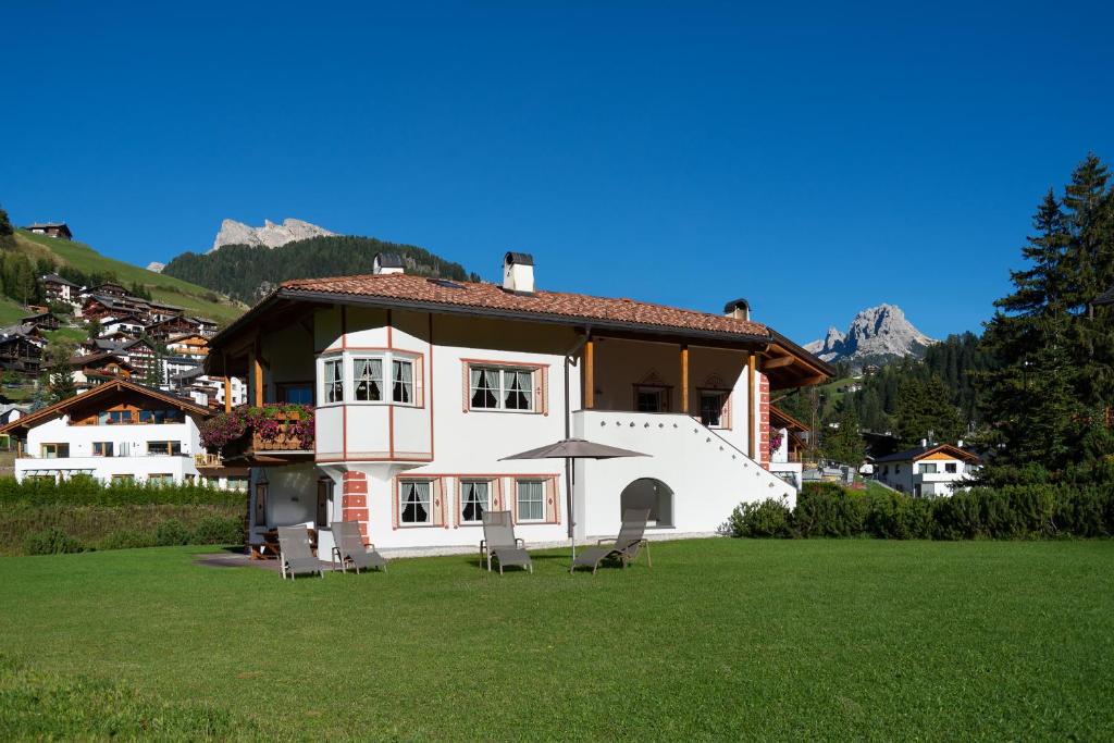 a large white house with two chairs and an umbrella at Artitsch in Santa Cristina Gherdëina