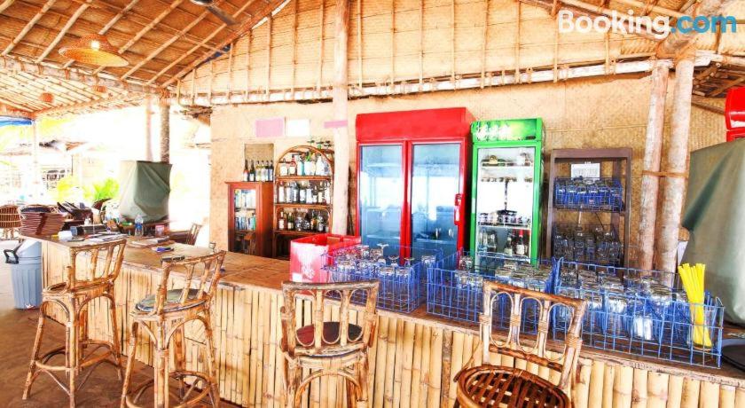 a restaurant with a bar with chairs and a soda machine at Blue Corner Beach Huts & Restaurant in Benaulim