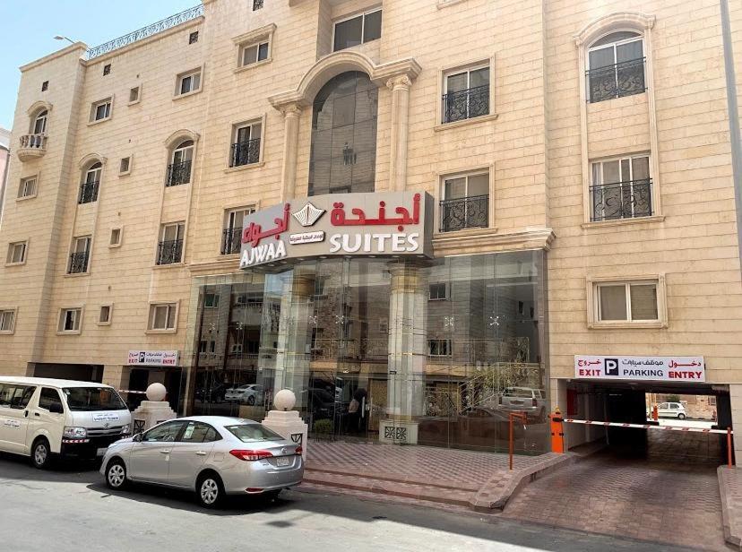 Ajwaa Suites في جدة: محل امام مبنى فيه سيارات متوقفه بالخارج