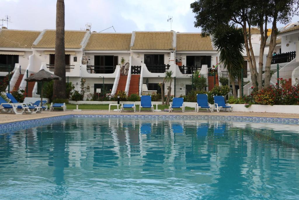 ラゴスにあるMoradia T2+1 COM PISCINAのホテル正面のスイミングプール(青い椅子付)