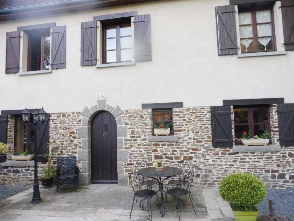 a house with black shutters and a table in front of it at La guesnonniere in Quibou