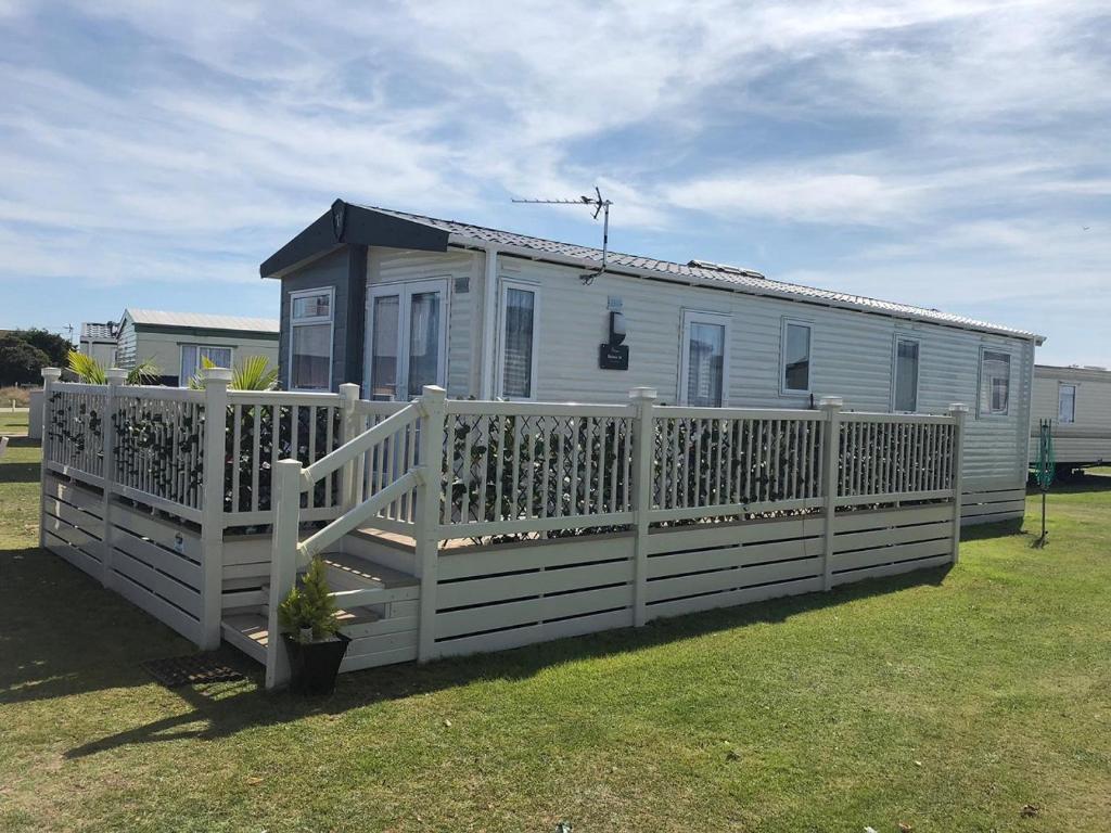 una pequeña casa con una valla blanca en un patio en Spacious Holiday Home - Romney Sands en Littlestone-on-Sea