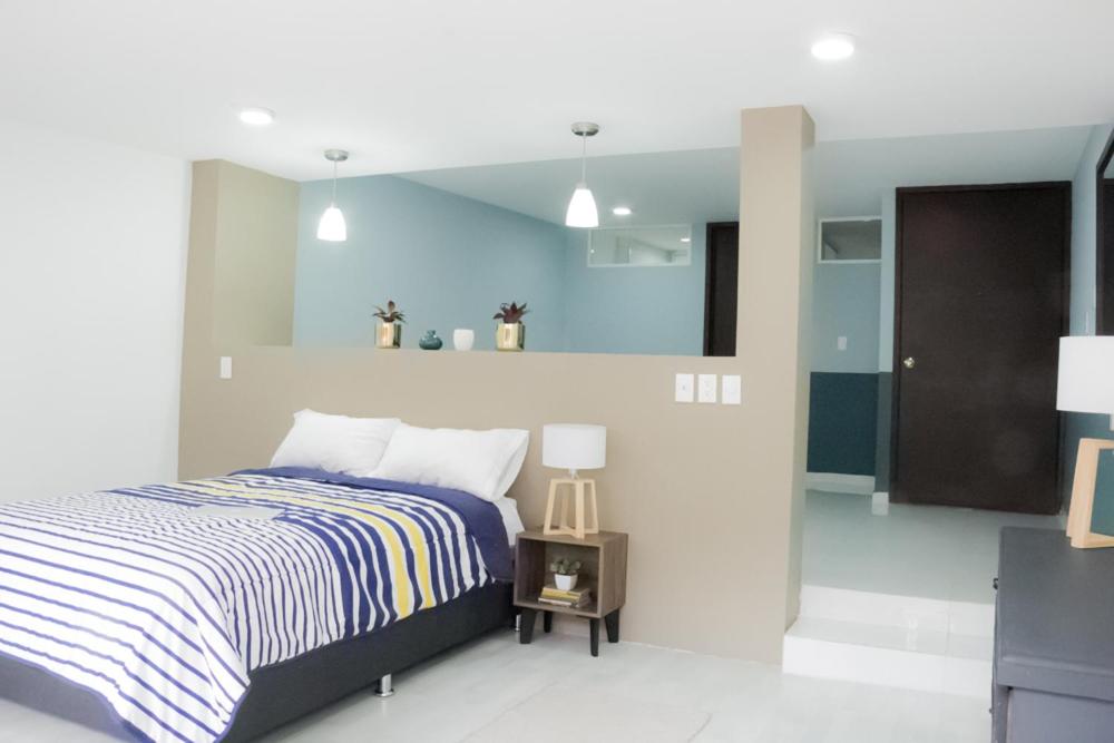 A bedroom with a striped bed, bedside table and partial divider.