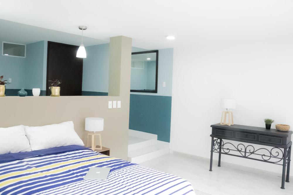 A wider bedroom view includes a decorative console and a laptop resting on the bed.