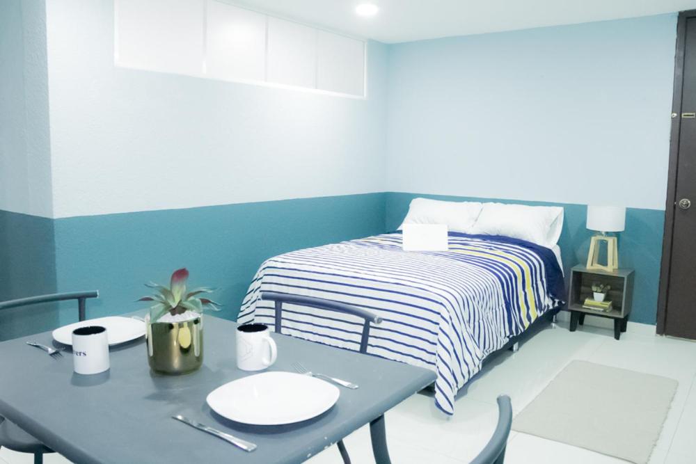 A combined sleeping and dining room with a blue accent wall and a two-seat table.