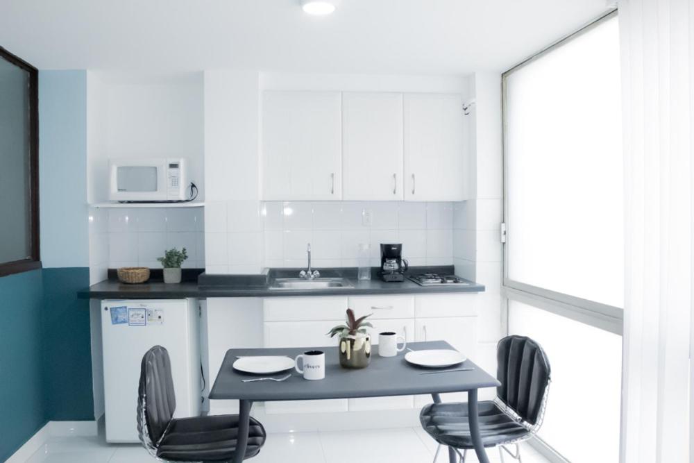 A compact kitchen-dining setup with a microwave, refrigerator and two-seat table.