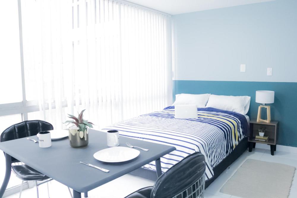 1 dormitorio con 1 cama y 1 mesa con sillas en Privada de Horacio 18 Residences, en Ciudad de México