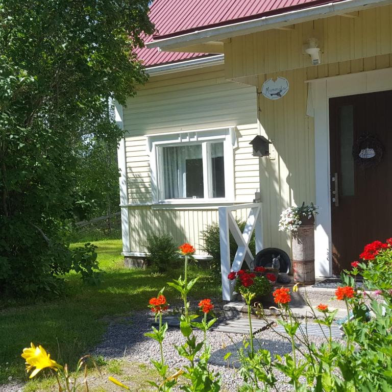 Villa Vuorenpää في Tammela: منزل أبيض صغير مزين بالزهور في فنائه