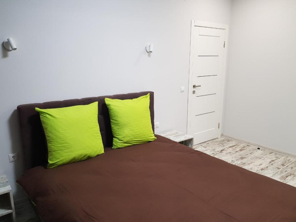 a bedroom with a bed with two lime green pillows at Silver Star Apartment 40b in Uzhhorod