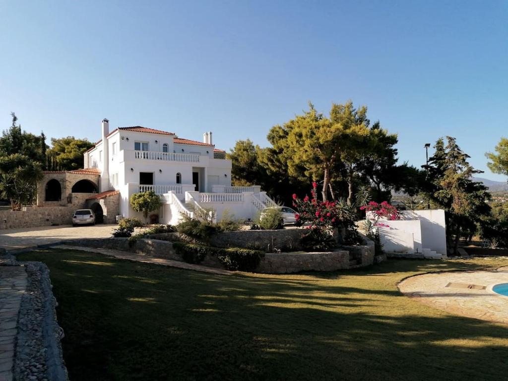 una casa bianca con un cortile davanti di Ktima Nafsika - Ground-floor luxury apartment in idyllic estate! a Porto Heli