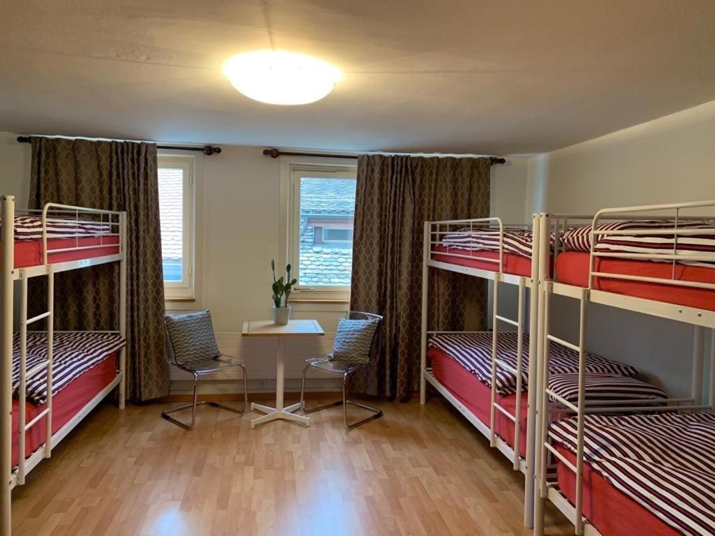 a room with three bunk beds and a table and chairs at Friendly Hostel Zürich in Zürich