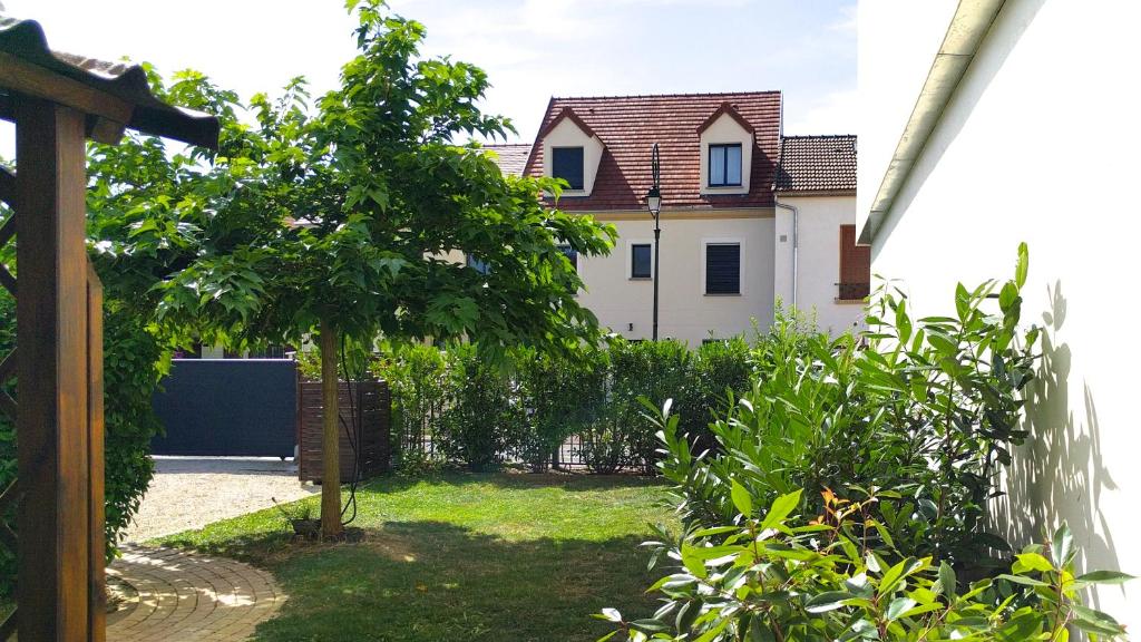 une maison avec un arbre en face d'une cour dans l'établissement Appartement les Acacias, à Clamart