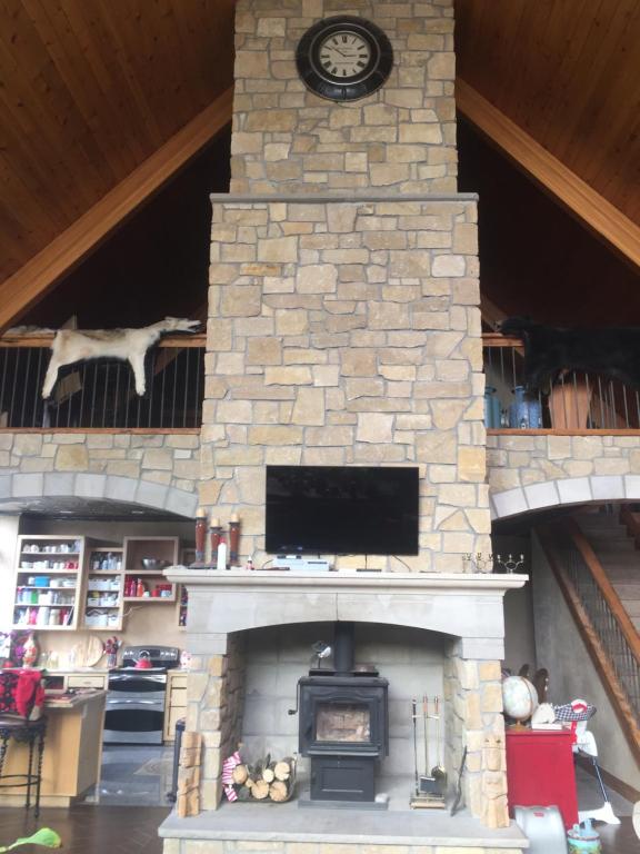 a stone fireplace with a clock on top of it at The Old Church B&B in Warner