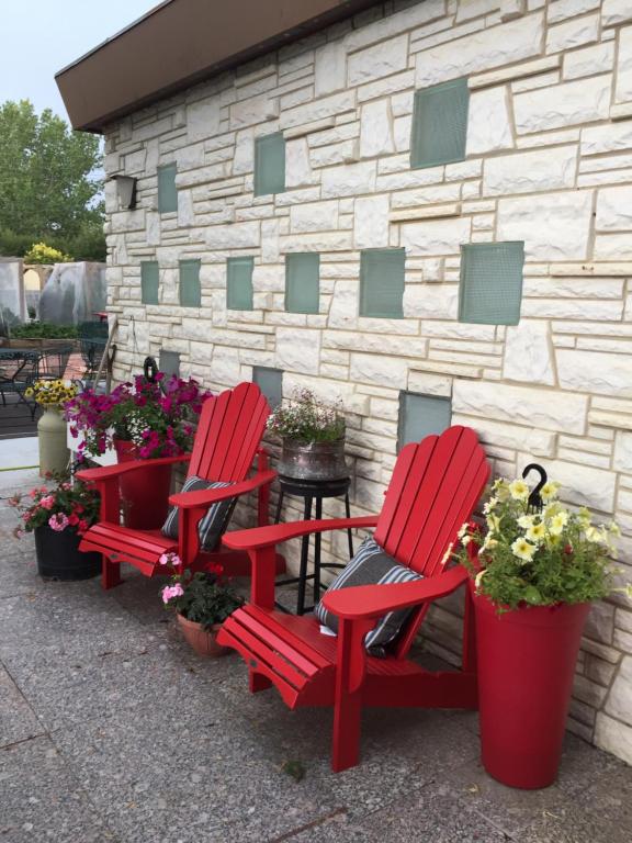 two red chairs and potted plants in front of a building at The Old Church B&B in Warner